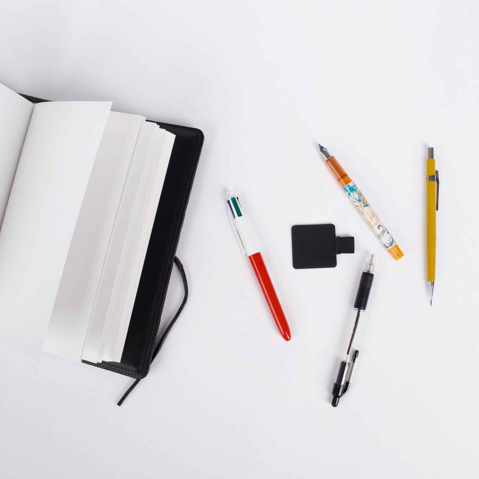 Leather and elastic Self-adhesive Pen Loop, grouped with pens and journal, by Oberon Design